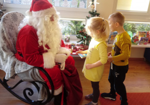 Mikołaj wręcza dzieciom cukierki