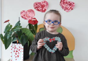 Dziewczynka siedzi trzymając serce z puzzli