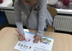 Dziewczynka rysuje w książeczce swój portret