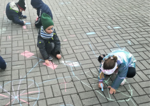 Dzieci malują kredami po chodniku