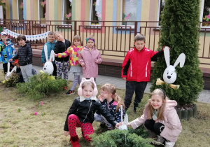 Dzieci przed przedszkolem wsród króliczków wielkanocnych