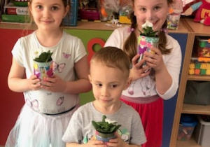 Dzieci prezentują wykonane doniczki z zasadzonymi kwiatami