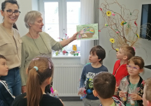 Dzieci wręczają wspólnie wykonaną kartkę świąteczną