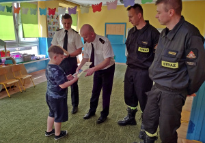 Chłopiec dziękuje strażakom i odbiera dyplom