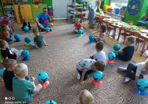 Dzieci siedzą z piłkami.