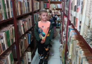 Dziewczynka stoi miedzy regałami książek