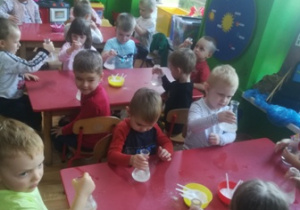 dzieci siedzą przy stolikach.