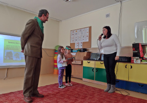 Leńniczy przyjmuje nagrodę od przedszkolaków