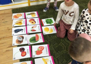 Chłopiec układa zdjęcia owoców i warzyw.
