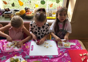 Dzieci kroją owoce na deskach.