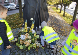 Dzieci stawiają znicze przed pomnikiem Jana Pawła II