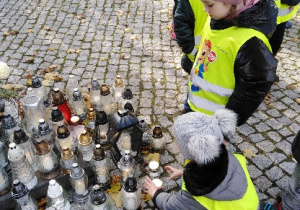 Dzieci ustawiają znicze pod pomnikiem Jana Pawła II