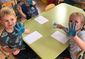Dzieci pokazują pomalowane na niebiesko dłonie