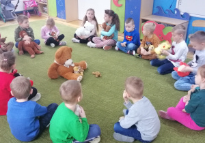 Dzieci siedząc w kole przedstawiaj misie i swoje ulubione zabawki