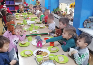 Dzieci wraz z misiami jedzą śniadnia