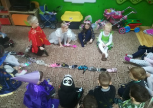 Dzieci układają ,jeden za drugim, swoje buty na dywanie