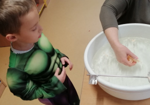 Chłopiec obserwuje proces zastygania wosku wodzie