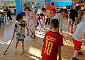 Dzieci ćwiczą z laskami gimnastycznymi