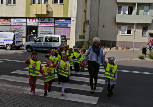 Dzieci na spacerze przechodzą przez jezdnię