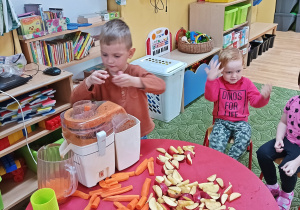Dzieci wkładają do sokowirówki owoce