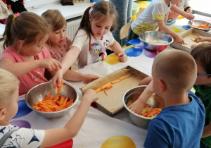 Dzieci układają warzywa na brytfannach