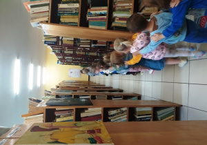 Dzieci jada pociągiem pomiędzy regałami książek