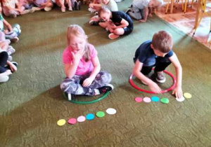 Dziewczynka i chłopiec układają wzór z kół na dywanie