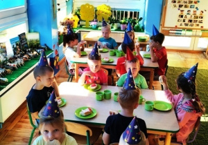 Dzieci jedzą śniadanie przy stolikach