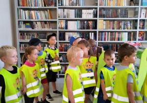 Dzieci stoją w pomieszczeniu bibliotecznym