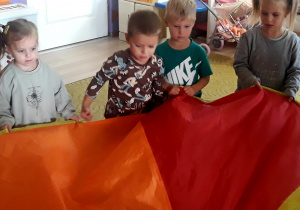 Dzieci trzymają chustę animacyjną z balonikami