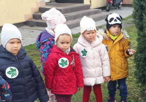 Dzieci stoją w ogrodzie przedszkolnym