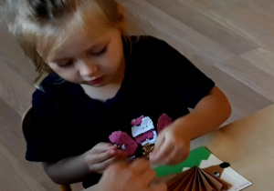 Dziewczynka wykonuje jeża z papieru