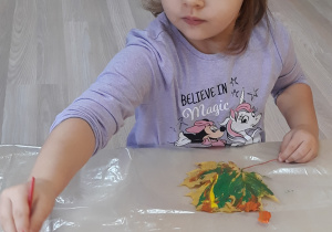 Dziewczynka maluje liść farbami