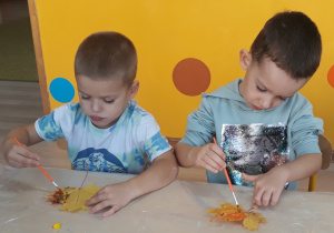 Chłopcy malują liść farbami