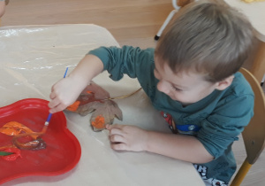 Chłopiec maluje liść farbami