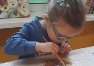 Dziewczynka maluje liść farbą