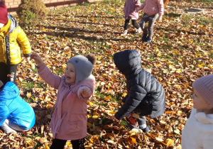 Dzieci bawią się liśćmi w ogrodzie przedszkolnym