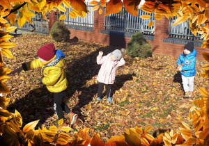 Dzieci bawią się liśćmi w ogrodzie
