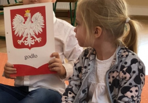 Chłopiec trzyma ilustrację z godłem Polski