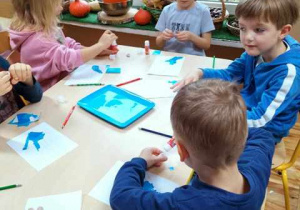 Dzieci wykonują prace plastyczna przy stolikach