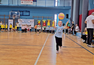 Dziewczynka biegnie, podrzucając piłkę do siatkówki