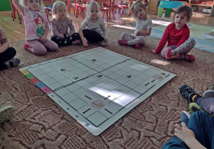 Dzieci grają w grę z ęlementami kodowania "Głodna żyrafa"