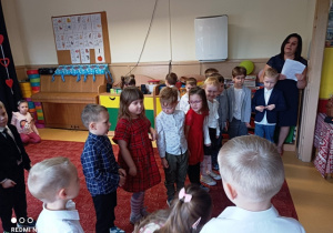Dzieci stoją w rzędzie i recytują wiersze