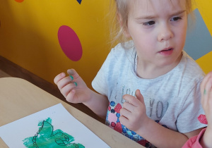 Dzieci stemplują gąbką umoczoną w farbie kontur dinozaura