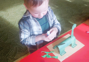 Chłopiec wykonuje dinozaura z papieru