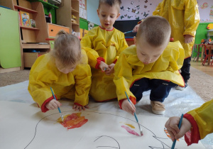 Dzieci malują farbami plakat dinozaura