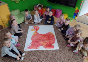 Dzieci pozują do zdjęcia z namalowanym plakatem dinozaura