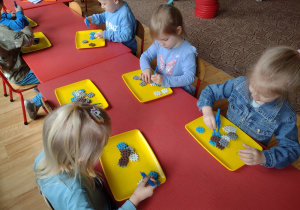 Dzieci ćwiczą umiejętność posługiwania się pensetą