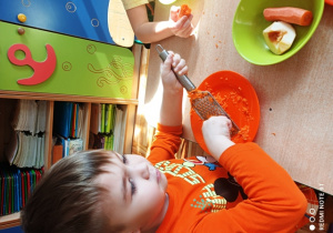 Chłopiec ściera marchewkę na tarce