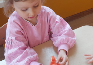 Dziewczynka wykonuje marchewkę z folii i bibuły